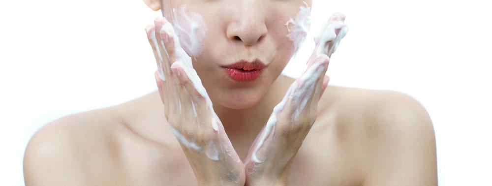 bột rửa mặt. Phụ nữ châu Á rửa mặt bằng bọt làm sạch