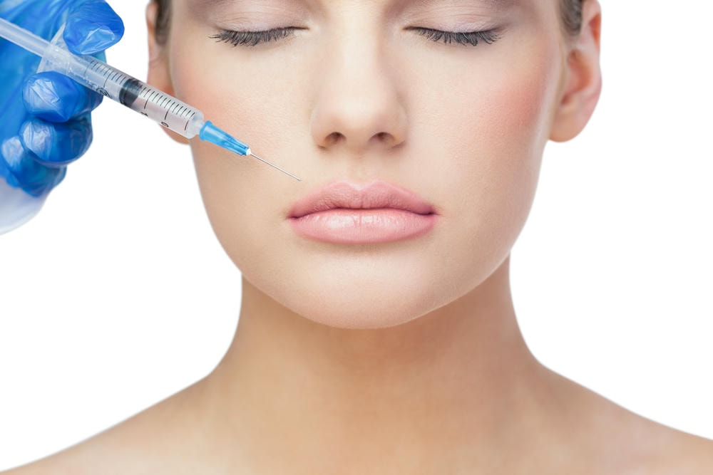 các dáng môi tiêm filler. Cô gái tóc vàng xinh đẹp thư giãn đang được tiêm lên môi