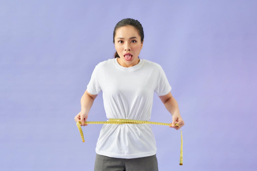 cách giảm cân nhanh nhất. Người phụ nữ trẻ đo vòng eo bằng dây