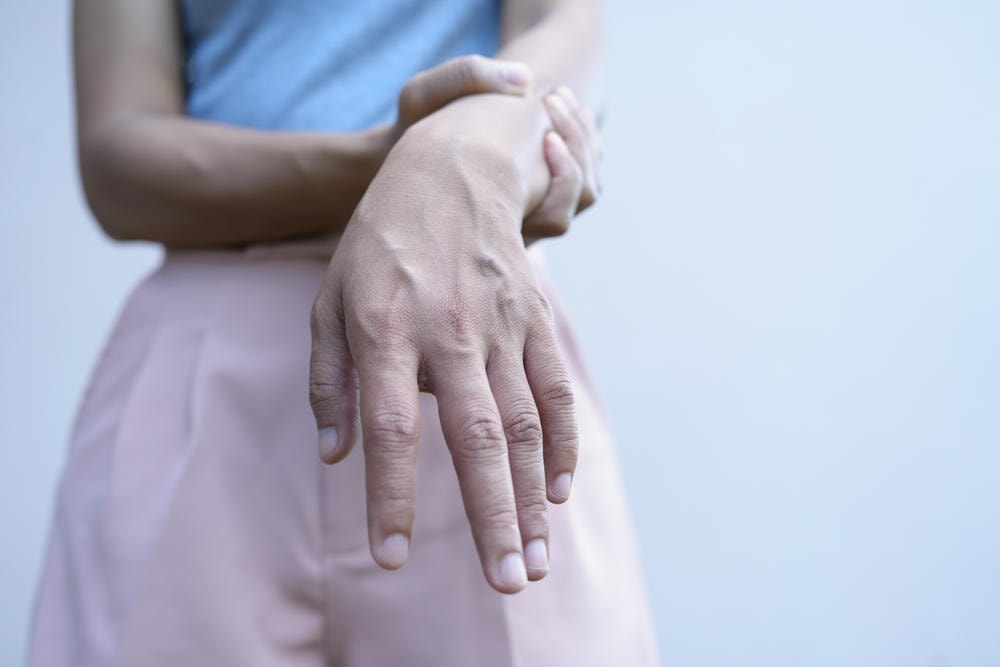 gân tay. Người phụ nữ châu Á bị yếu cơ yếu chi