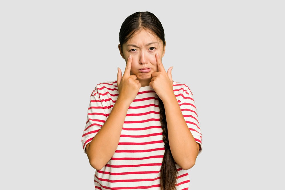hạ gò má. Người phụ nữ châu Á trẻ tuổi bị cô lập khóc không vui với một cái gì khái niệm đau khổ và bối rối