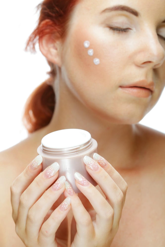 kem bôi da. Người phụ nữ thoa kem lên mặt