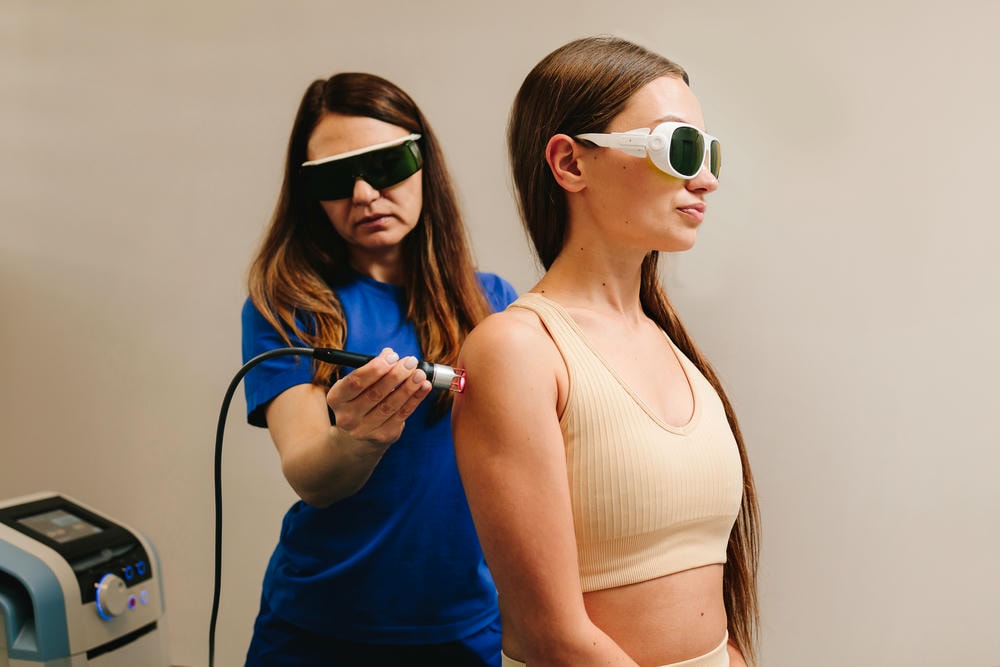 máy bắn laser. Liệu pháp laser cho đau lưng mãn tính Người phụ nữ đang chữa lành bằng ánh sáng đỏ để giảm đau viêm và phù nề ở lưng của cô ấy Liệu pháp laser hiệu quả để phục hồi các mô cơ và dây thần kinh bị tổn thương