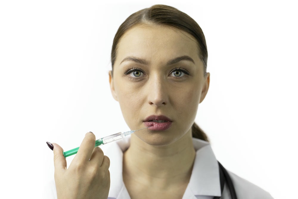 tiêm filler bị cứng bao lâu. Cô gái trẻ quyến rũ với làn da khỏe mạnh tiêm botox vào môi, nạn nhân của sắc đẹp