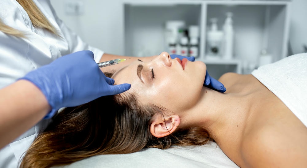tiêm meso căng bóng da. Cô gái chuyên viên làm đẹp tiêm vào môi và mặt của một người phụ nữ xinh đẹp trong một spa thẩm mỹ. Khái niệm thẩm mỹ.