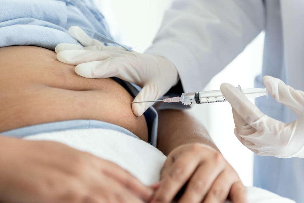 tiêm tan mỡ. Hình ảnh mềm mại bị mờ, Bác sĩ sắp tiêm vắc xin insulin vào bụng, bệnh nhân béo phì