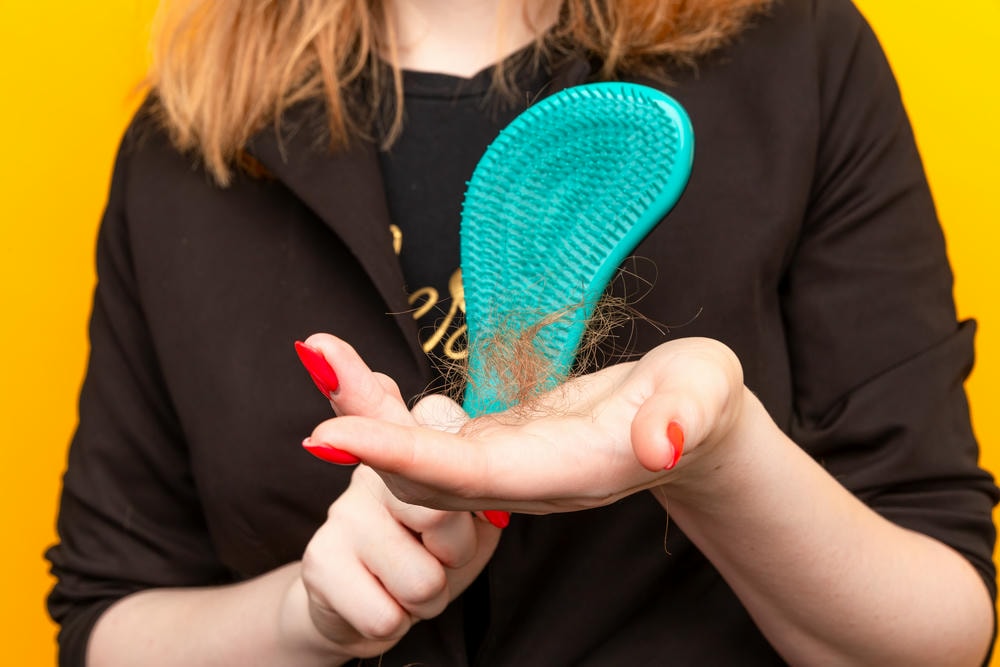 tóc rụng nhiều. Người phụ nữ trẻ lo lắng về rụng tóc trên nền trắng.